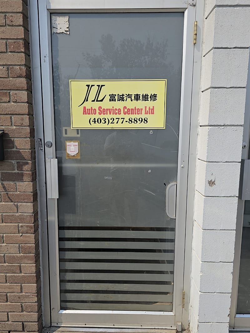 Glass entrance door of Unit 9 with a yellow sign reading JL 富誠汽車維修 Auto Service Center Ltd and the phone number