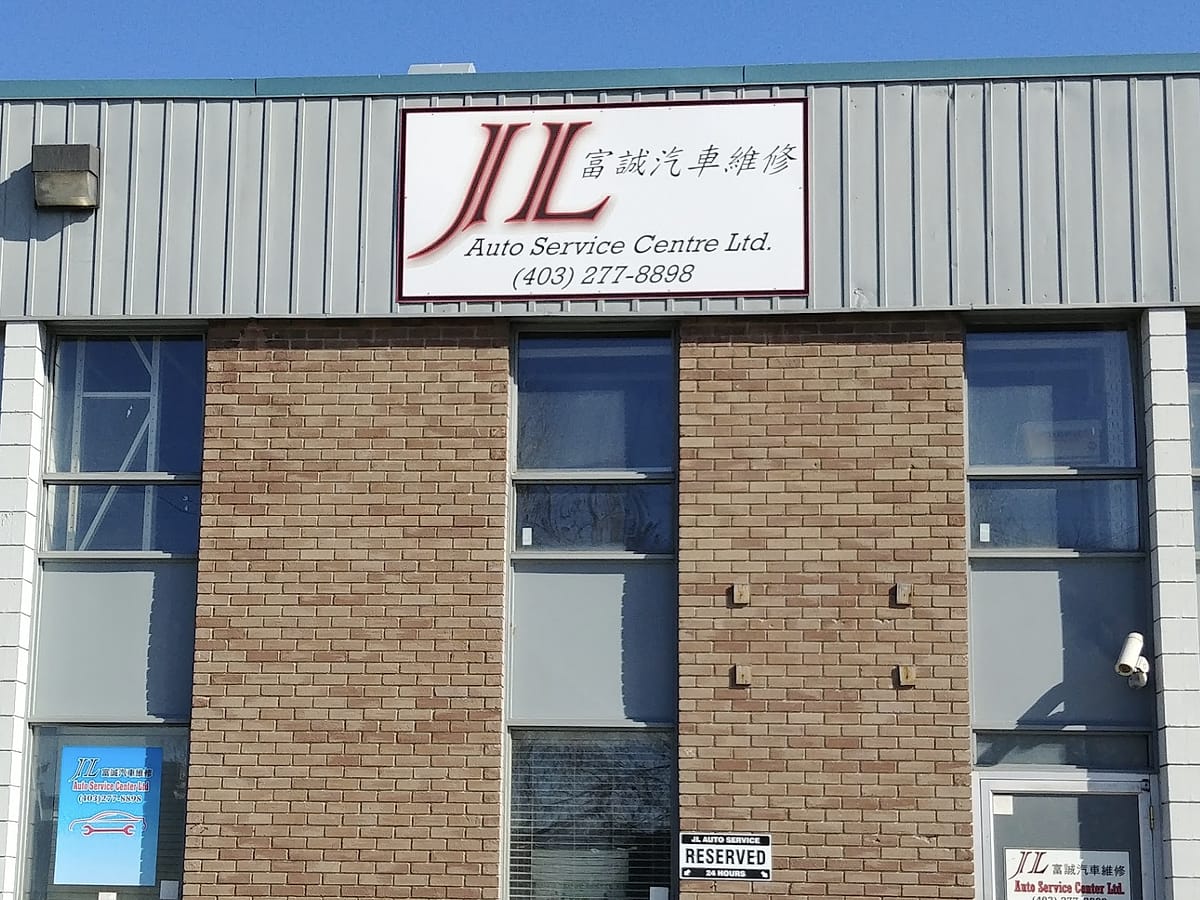 The red JL Auto Service Centre sign with the Chinese name 富誠汽車維修 above Unit 9, a brick bay at 1404 44 Ave NE in Calgary